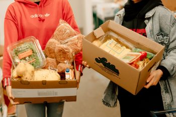Two people holding a food hampers